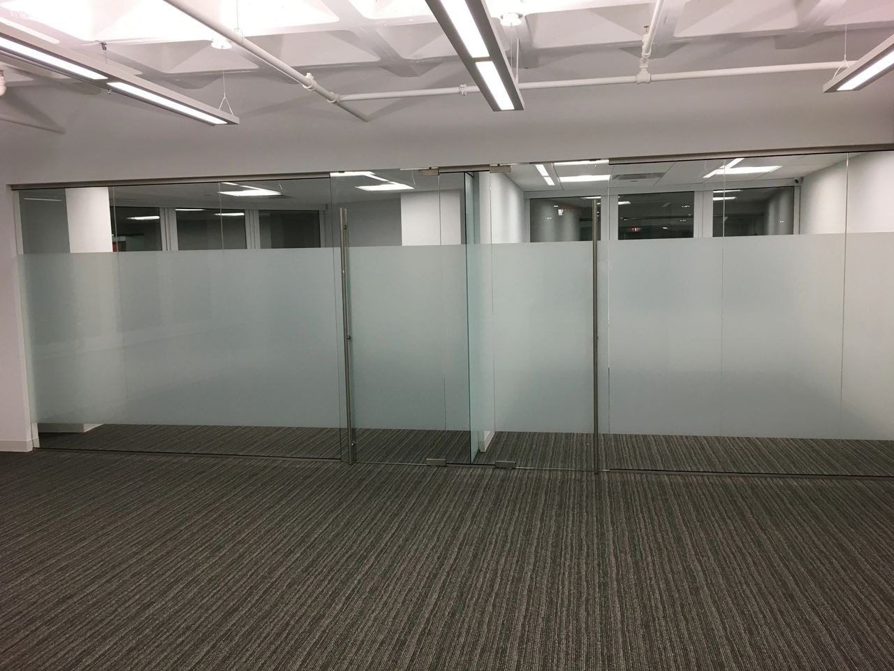 A room with glass walls and carpet flooring.