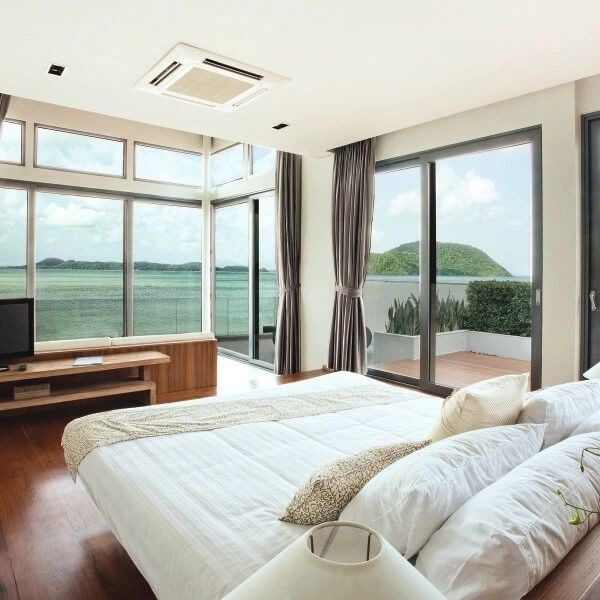 A bedroom with large windows and a view of the ocean.