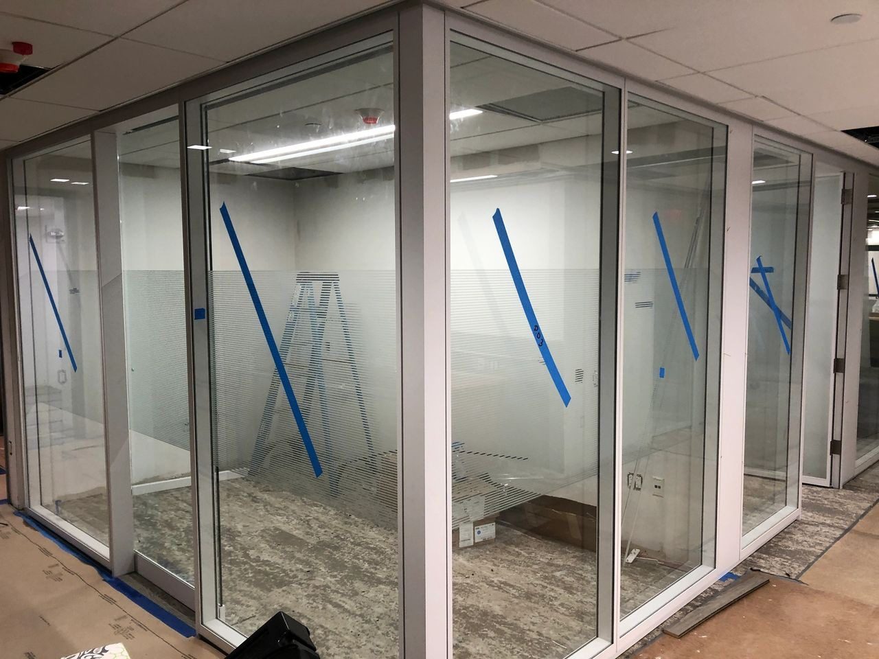 A room with glass walls and blue tape on the floor.
