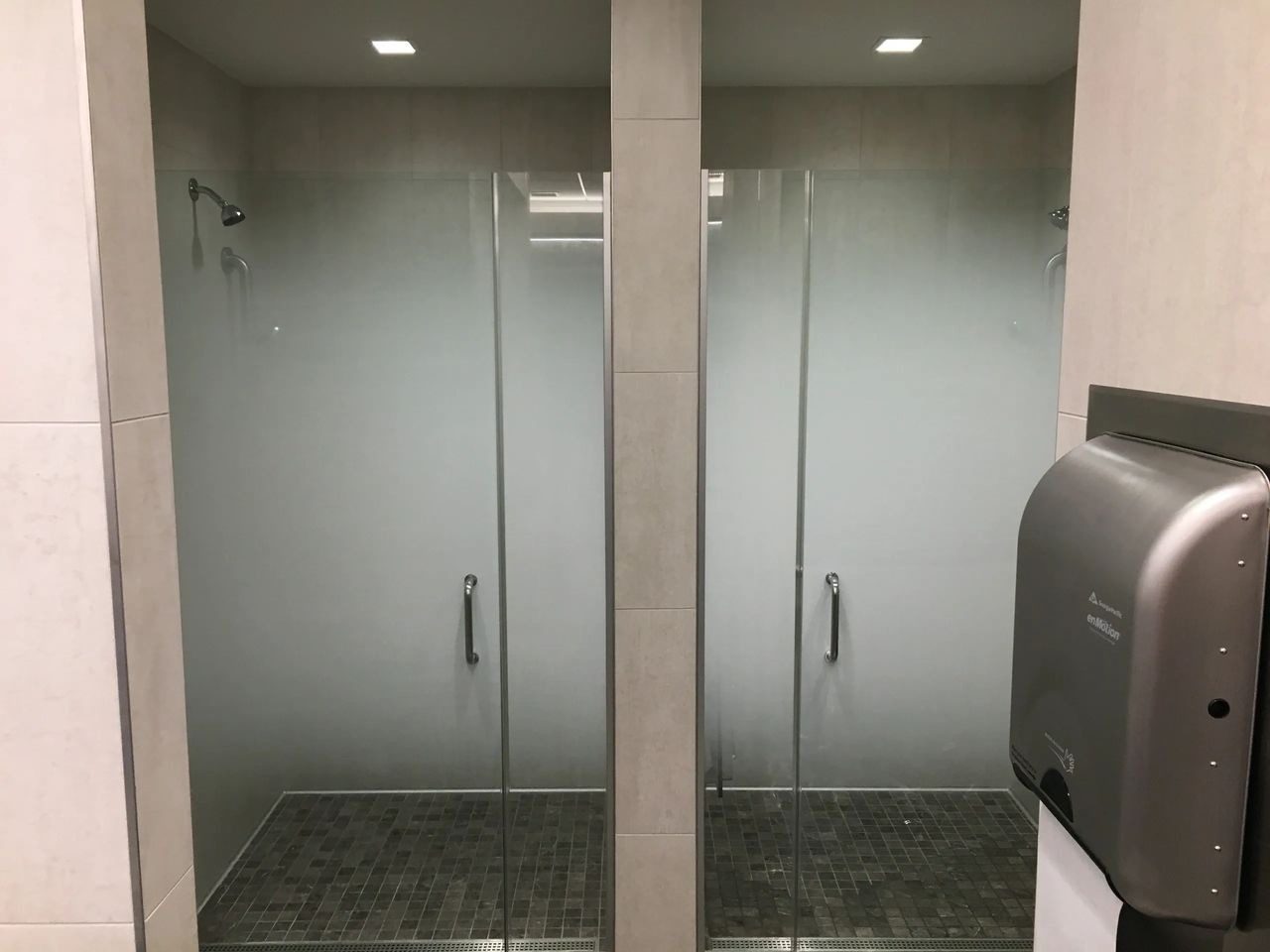 A bathroom with two glass shower doors and a sink.
