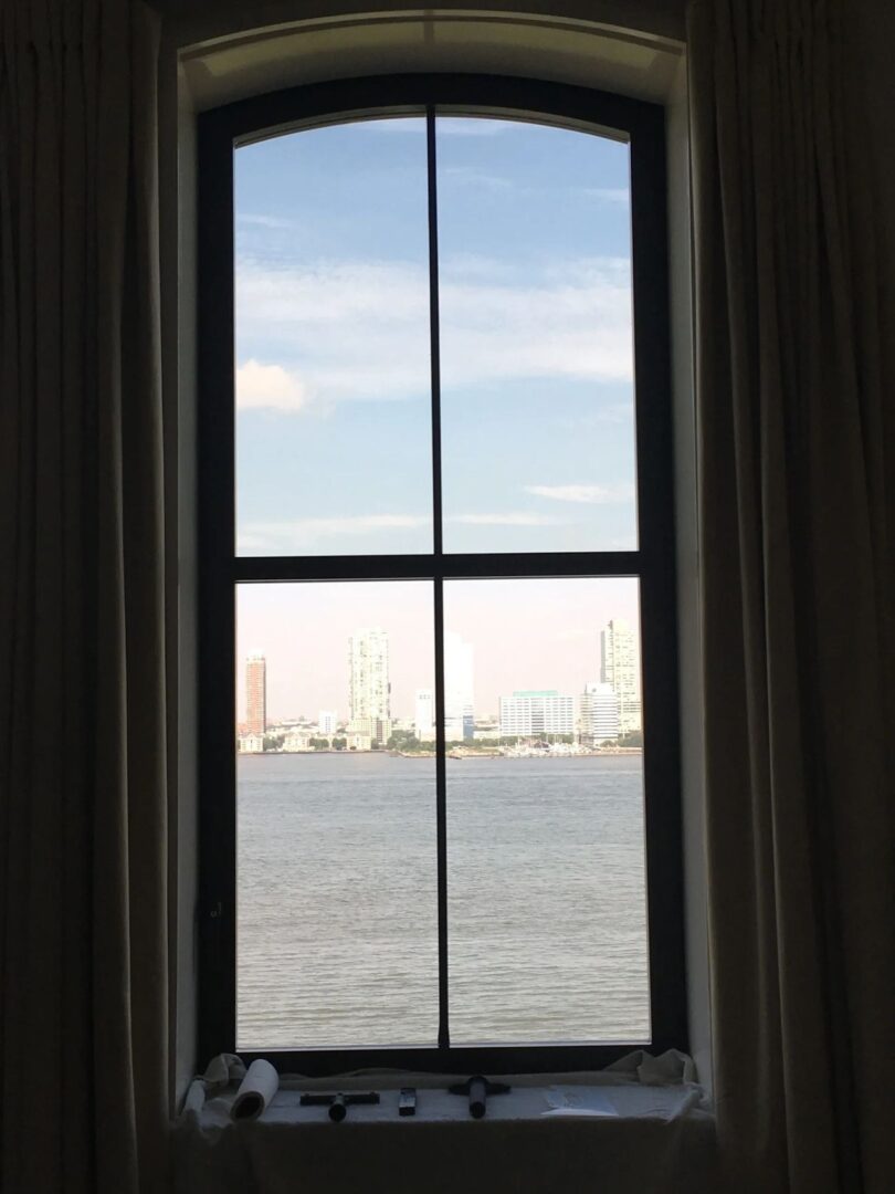 A window with curtains and a view of the water.
