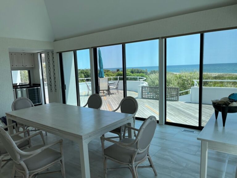 A dining room table with chairs and a view of the ocean.