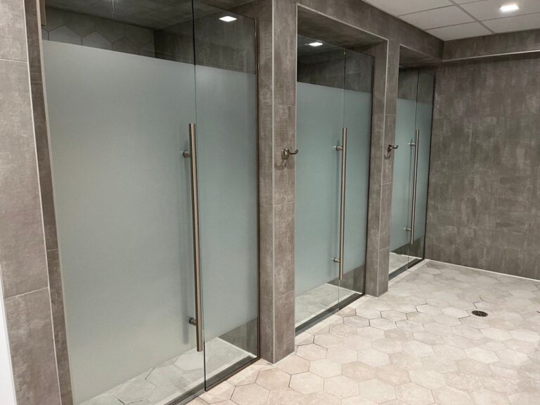 A bathroom with many glass doors and tiled floors.