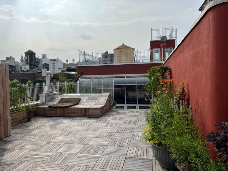 A patio with a red wall and a building